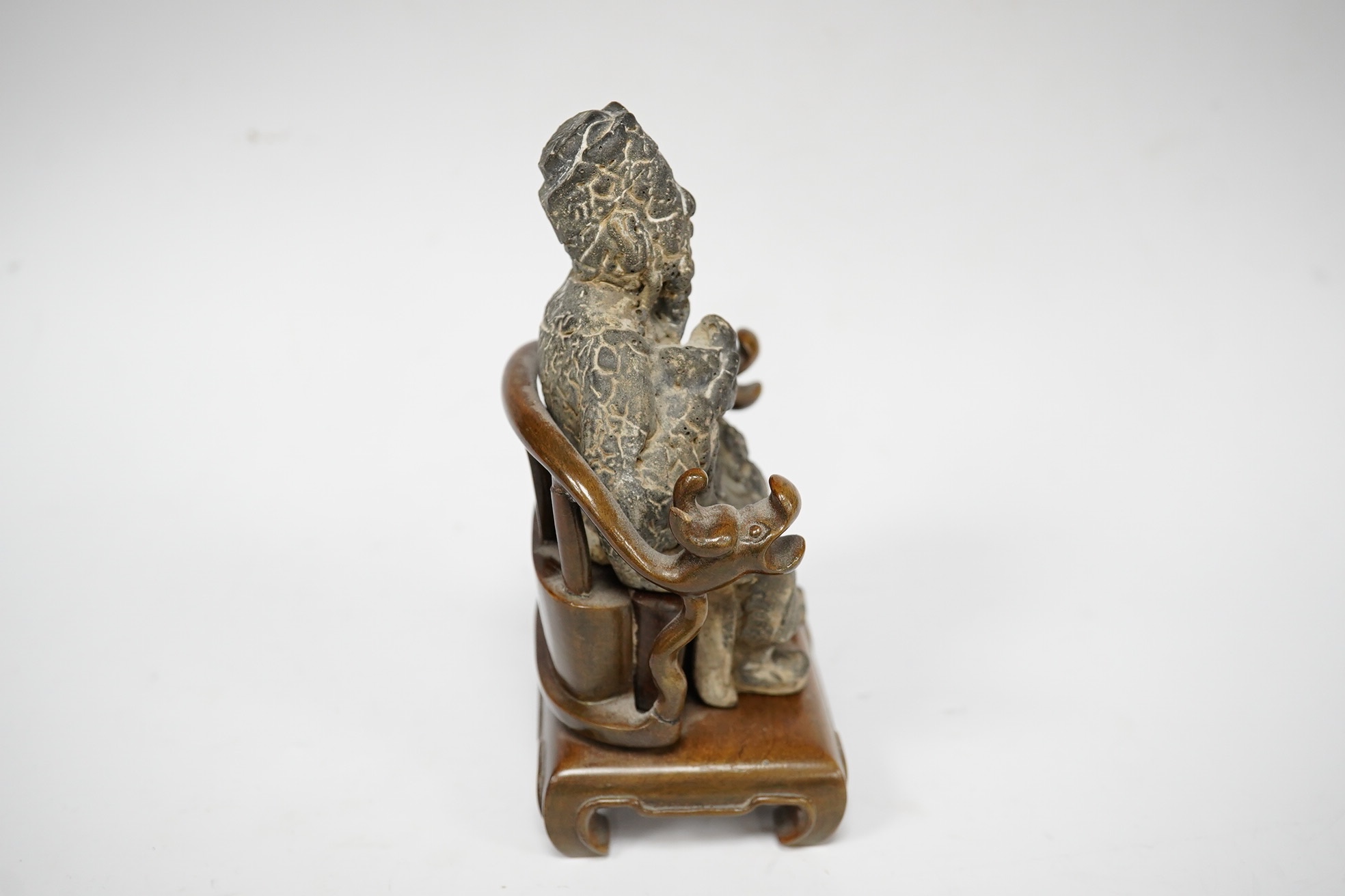 A Chinese grey pottery seated figure of a God, possibly Ming dynasty, seated on a later wood throne (with receipt of purchase from C C Tih Gallery, Hong Kong, 1968), 15cm high. Condition - fair